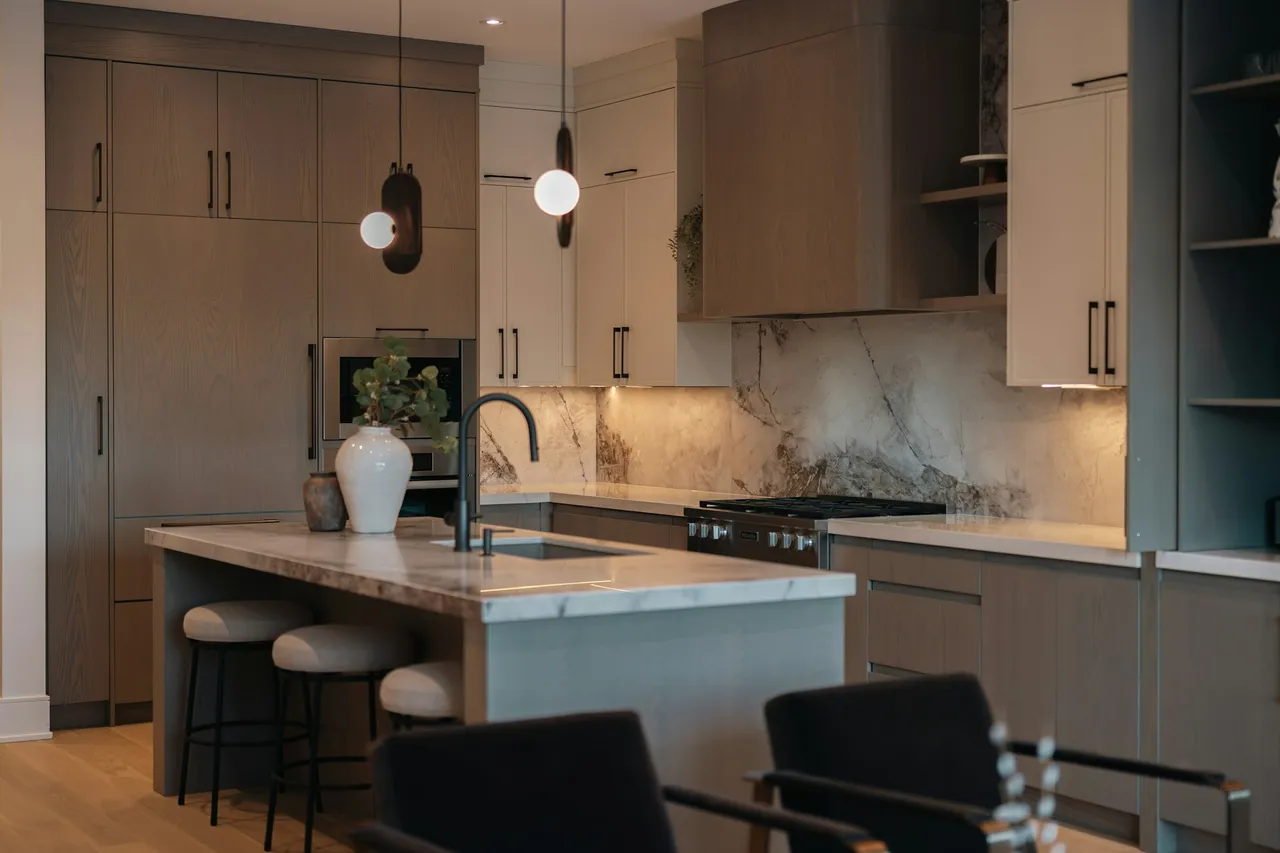 Wood cabinetry, a pale stone island, and warm pendant lighting in a contemporary kitchen.