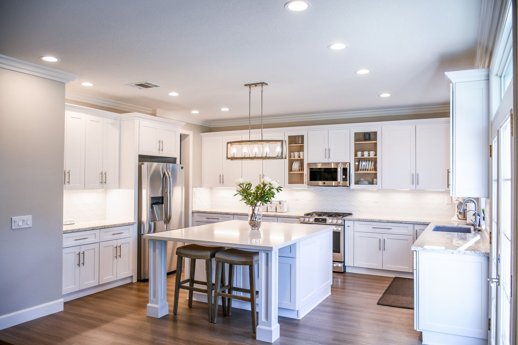 Bright white kitchen with an island and wood flooring, shown as design inspiration